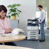woman reading and man working on a printer in an office